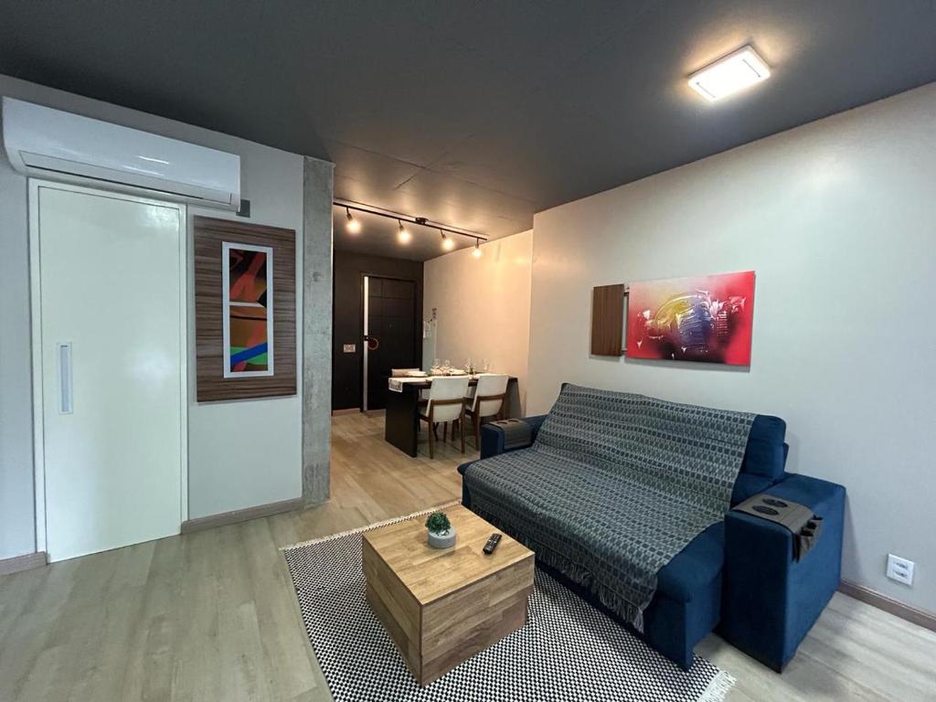 a living room with a blue bed and a table at Loft Praia Brava - Itajaí Camboriú piscina e playground in Itajaí