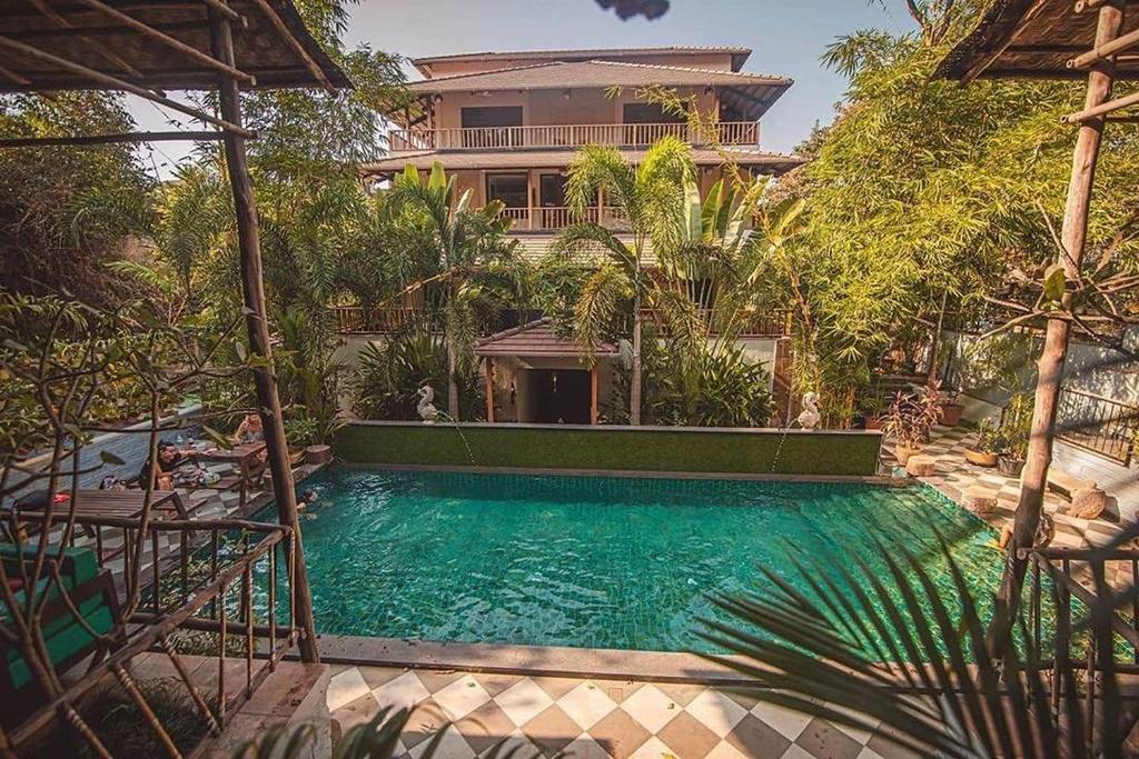 a swimming pool in front of a house at Anamiva, Goa - AM Hotel Kollection in Anjuna