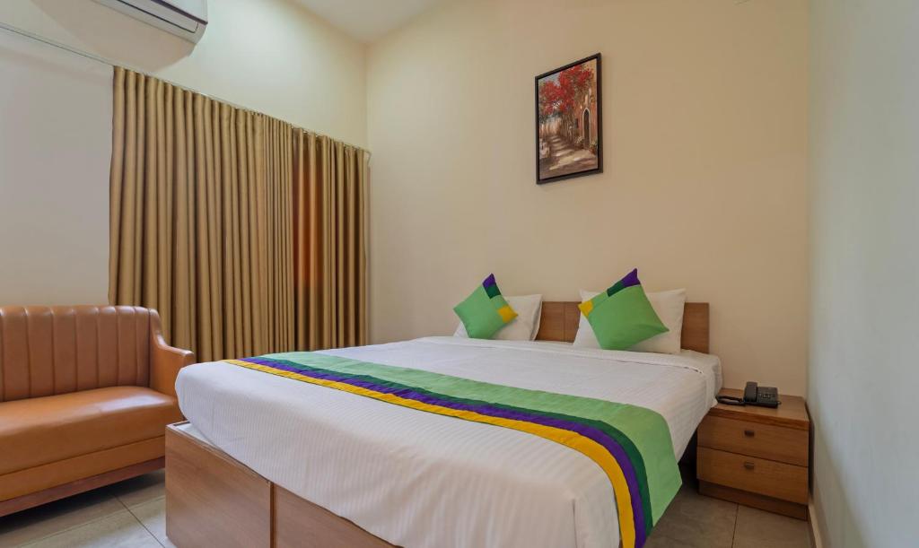a bedroom with a large bed and a chair at Itsy By Treebo - Avani Stays - Vyttila, Kochi in Ernakulam