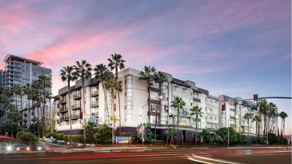 a building with palm trees in front of a street at Casa Marina - Modern, Stylish, Secure & Spacious Condo with 2 Master Suites in MDR & Close to Venice Beach in Los Angeles