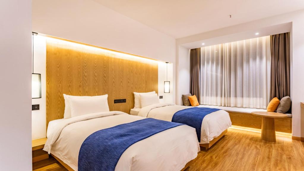 a hotel room with two beds and a window at Supu Hotel - Zhengzhou CBD International Convention and Exhibition Center in Zhengzhou