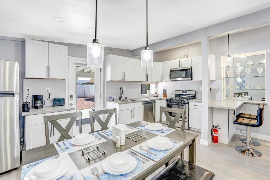 a kitchen with white cabinets and a table with plates on it at Fully Remodeled, Landscaped, King Beds, Desk Space in Las Vegas