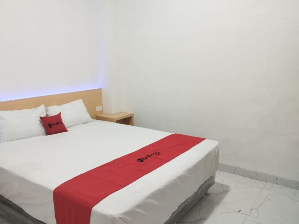 um quarto com uma cama com um cobertor vermelho e branco em RedDoorz Syariah @ Gedong Air Lampung em Kedaton