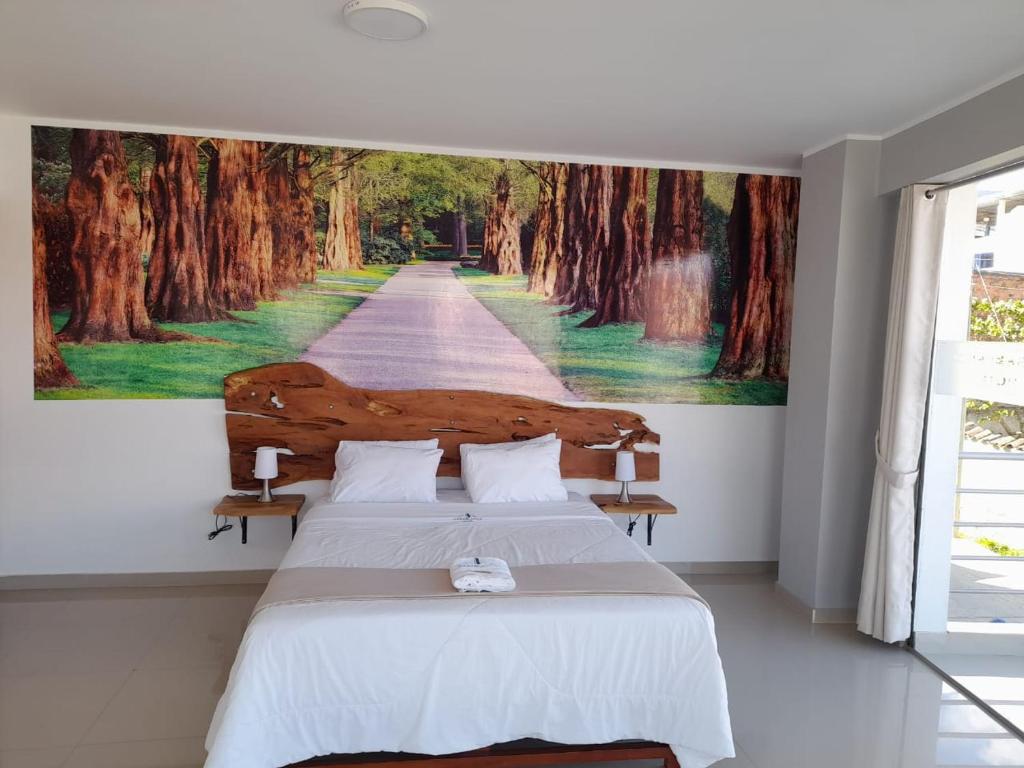 1 dormitorio con 1 cama con una pintura en la pared en CasaBlanca Hotel, en Huambo