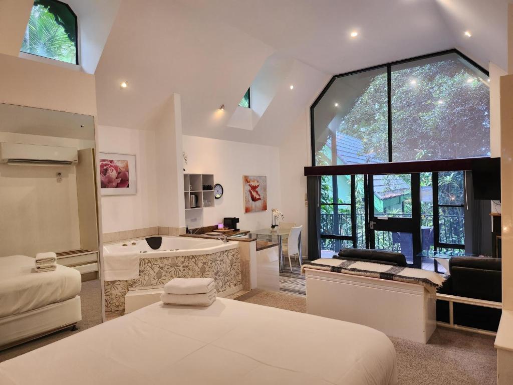 a bedroom with a bed and a bathroom with a tub at Gallery Walk Chalets - Tamborine Mountain in Mount Tamborine