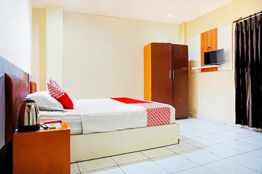 ein Schlafzimmer mit einem Bett mit roten Kissen in der Unterkunft COLLECTION O 91331 Hotel Grand Saota Soppeng in Watansopeng