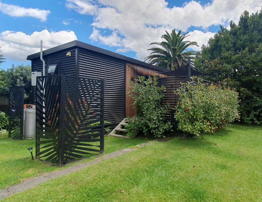 a black tiny house with a gate in a yard at Private Cabin in Waihi