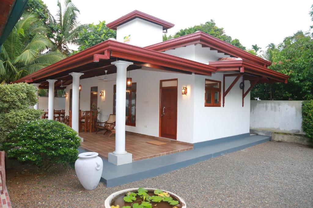 Casa blanca pequeña con terraza de madera en Rupa Villa, en Beruwala