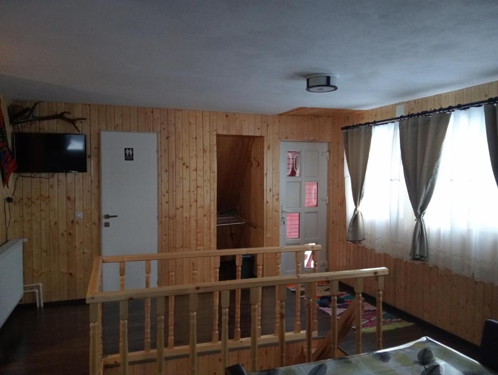 Habitación con paneles de madera, escalera y ventana. en Cabana Daria, en Gârda de Sus