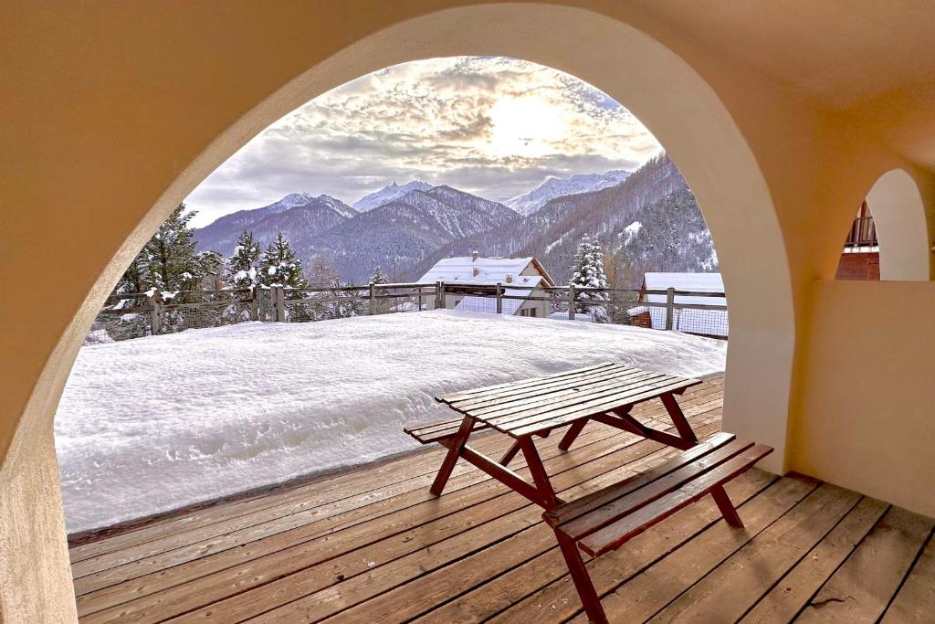 a wooden deck with a bench in front of a window at CASA-Joubarbe 4p terrace in Arvieux in Arvieux