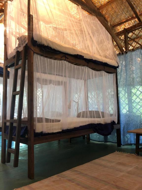 a bedroom with a canopy bed with white curtains at Bhakti Kutir in Palolem