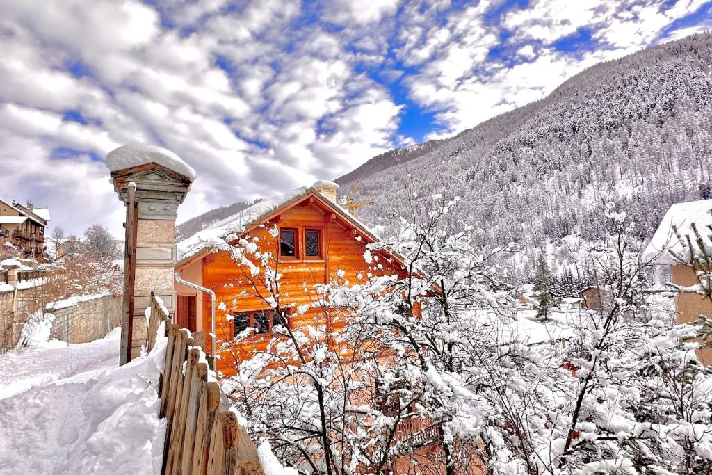 ein Holzhaus im Schnee mit einem Zaun in der Unterkunft CASA-Bruno family chalet Queyras 7p in Aiguilles