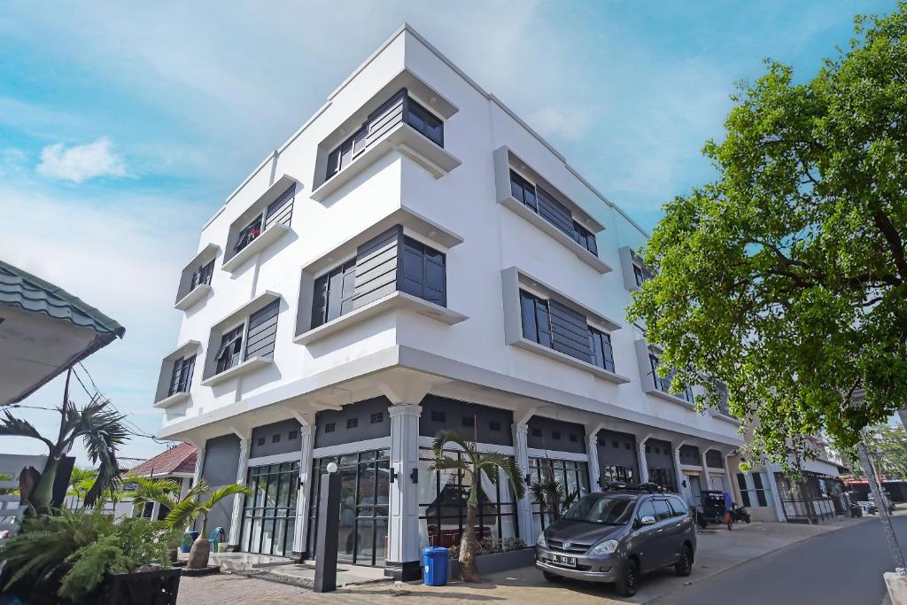 a white building with a car parked in front of it at Super OYO Capital O 92096 Kuala Ulee Lheue Residence Syariah in Banda Aceh