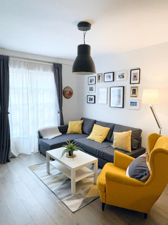 a living room with a blue couch and yellow chairs at Céntrico piso con parking disponible by beBalmy in Málaga