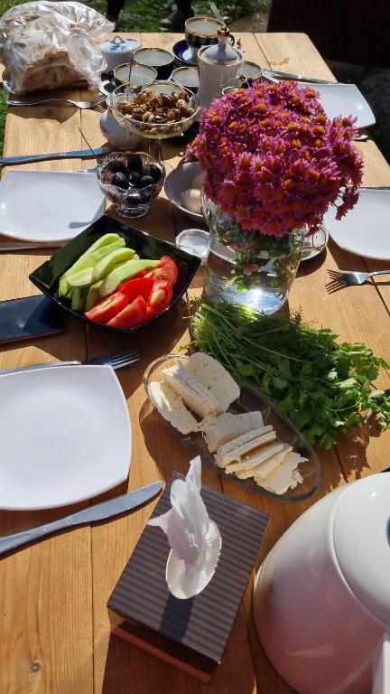 a wooden table with vegetables and a vase of flowers at Hooni_guesthouse in Odzun