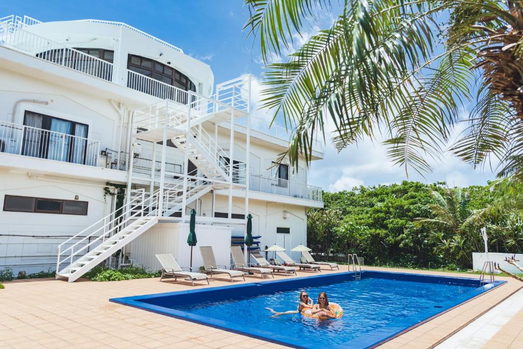 um grupo de pessoas numa piscina em frente a um edifício em リゾートイン青の洞窟 em Ishigaki