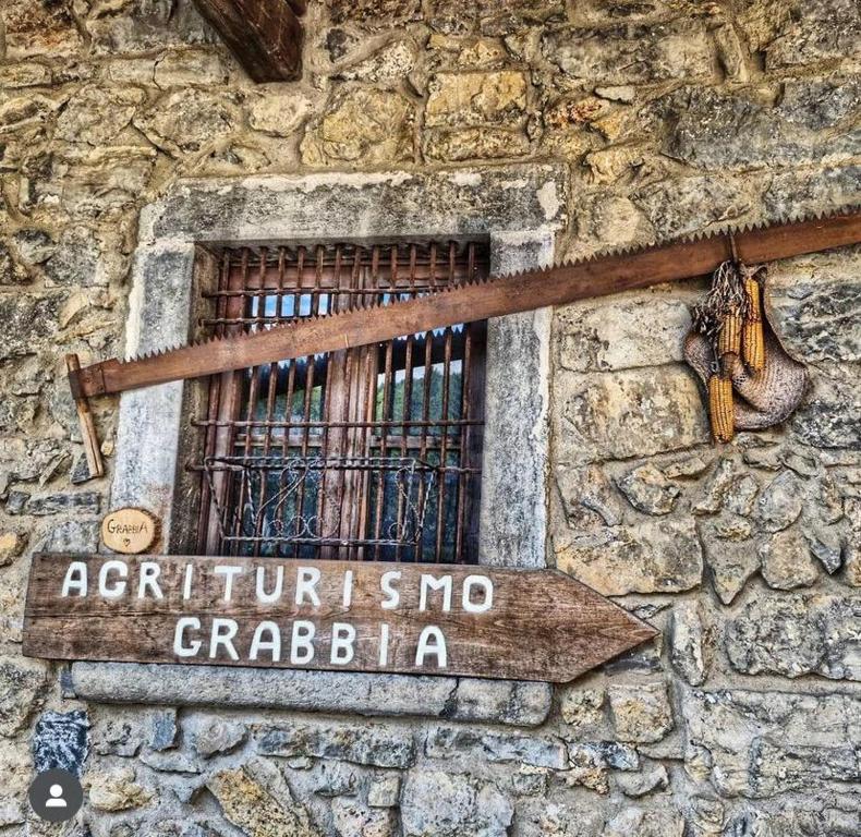 a sign on a stone building with a barred window at Agriturismo Grabbia in Grumo