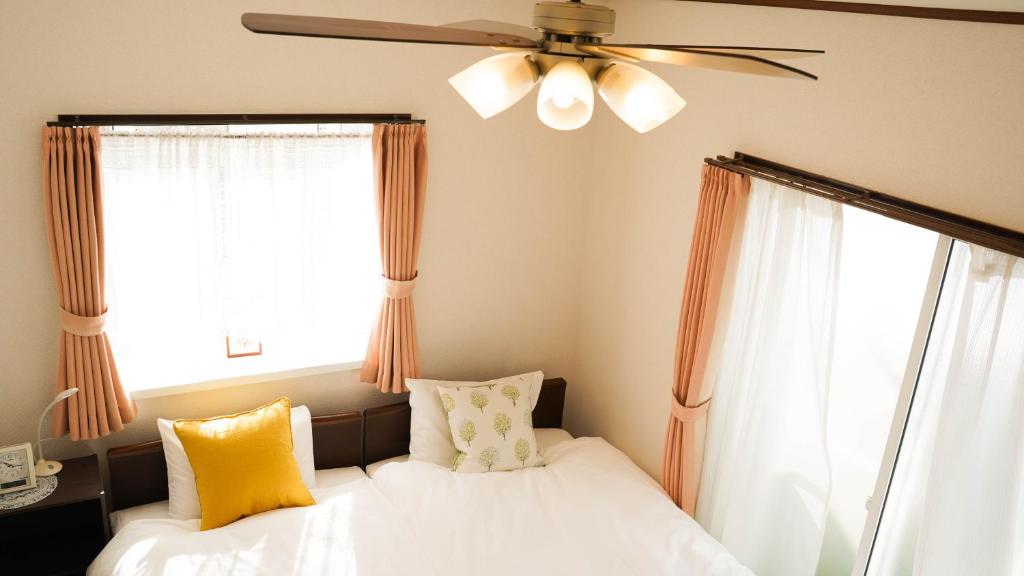 - une chambre avec 2 lits et un ventilateur de plafond dans l'établissement Casa Hakuba, à Hakuba