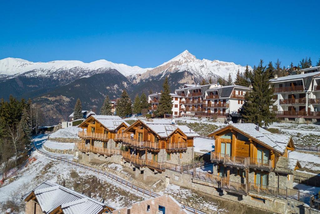 un complejo con montañas cubiertas de nieve en el fondo en Chalet Merveille Ski In - Ski Out, en Sauze dʼOulx