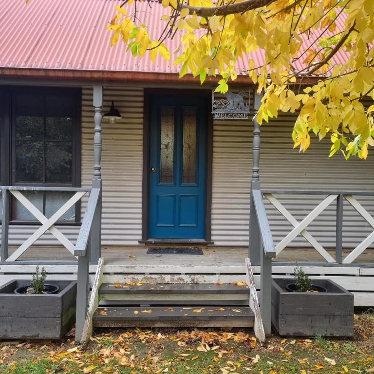 a house with a blue door and a porch at Giyabwe Cottage in Macclesfield
