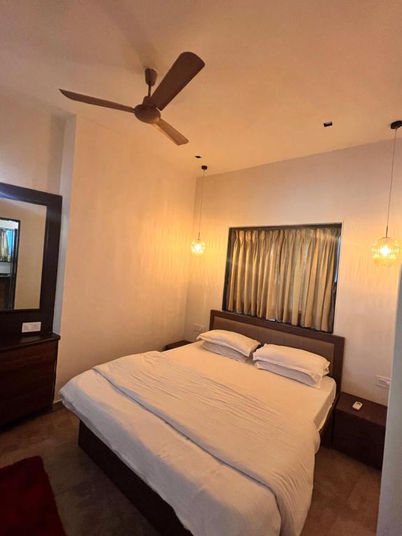 a bedroom with a bed with a ceiling fan at Villa by the Sea in Mumbai