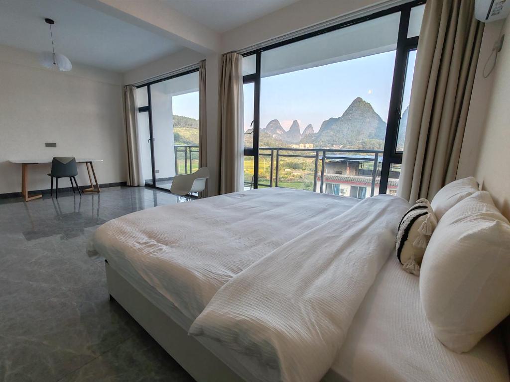 a bedroom with a large bed with a large window at shadow climers guest house in Yangshuo