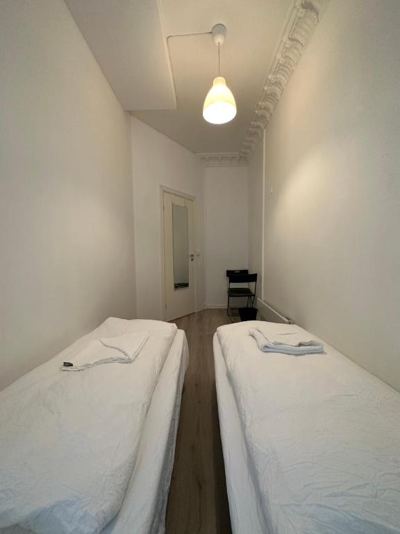 2 Betten in einem Zimmer mit weißen Wänden in der Unterkunft Concept Exodo Apartments in Oslo