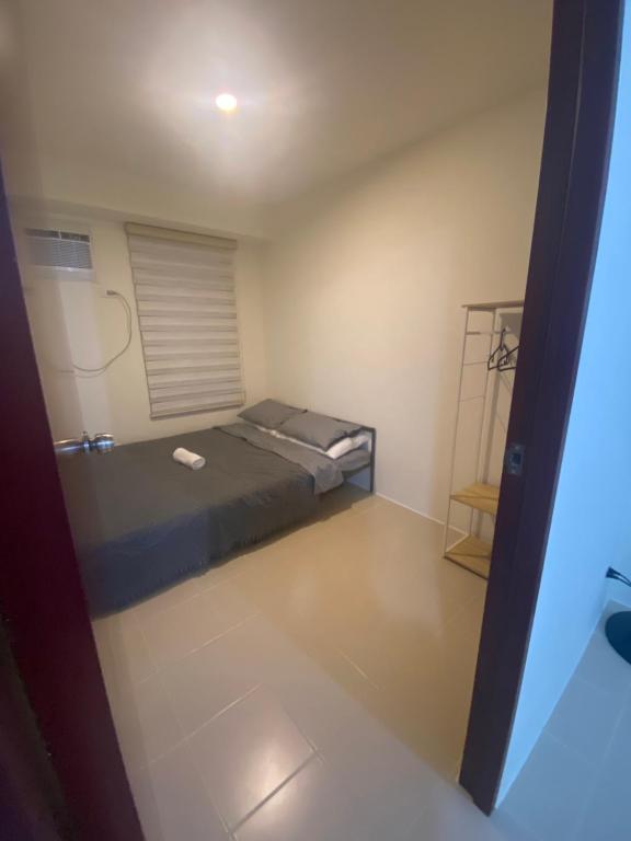 a small room with a bed and a mirror at Cozy 2-BR in UDH, Manila in Manila