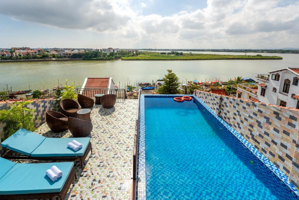 a swimming pool on top of a building next to a river at Rockmouse Centre River Villa Hoi An in Hoi An