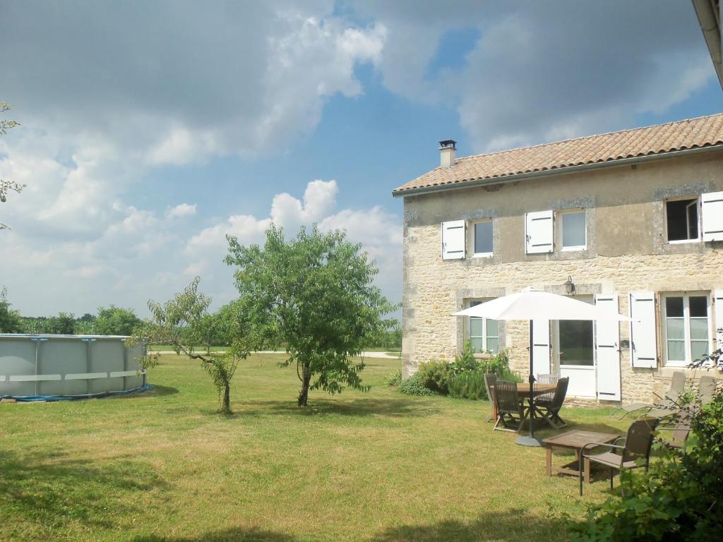 um edifício com uma mesa e cadeiras num quintal em Charente Chambres d'Hôtes - B&B em Bernac