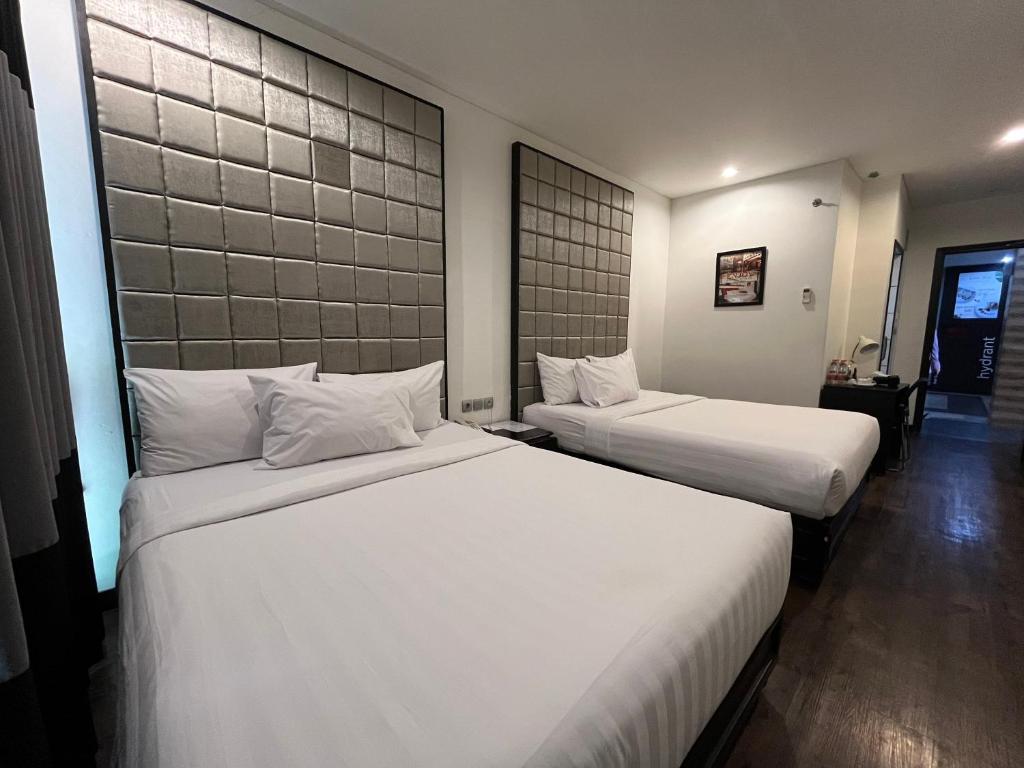 2 camas en una habitación de hotel con sábanas blancas en Kalya Hotel Bandung Dago, en Bandung