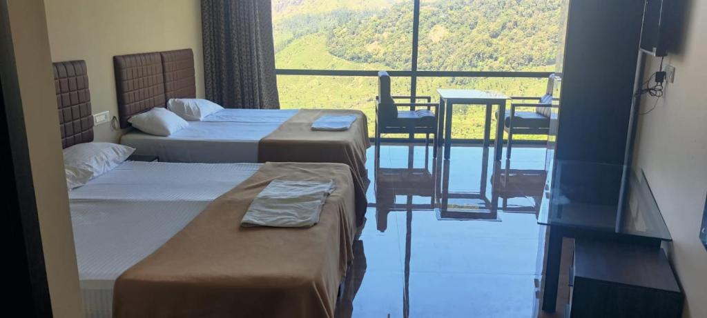 a room with two beds and a balcony with a table at BEAUTY SPOT MUNNAR in Munnar