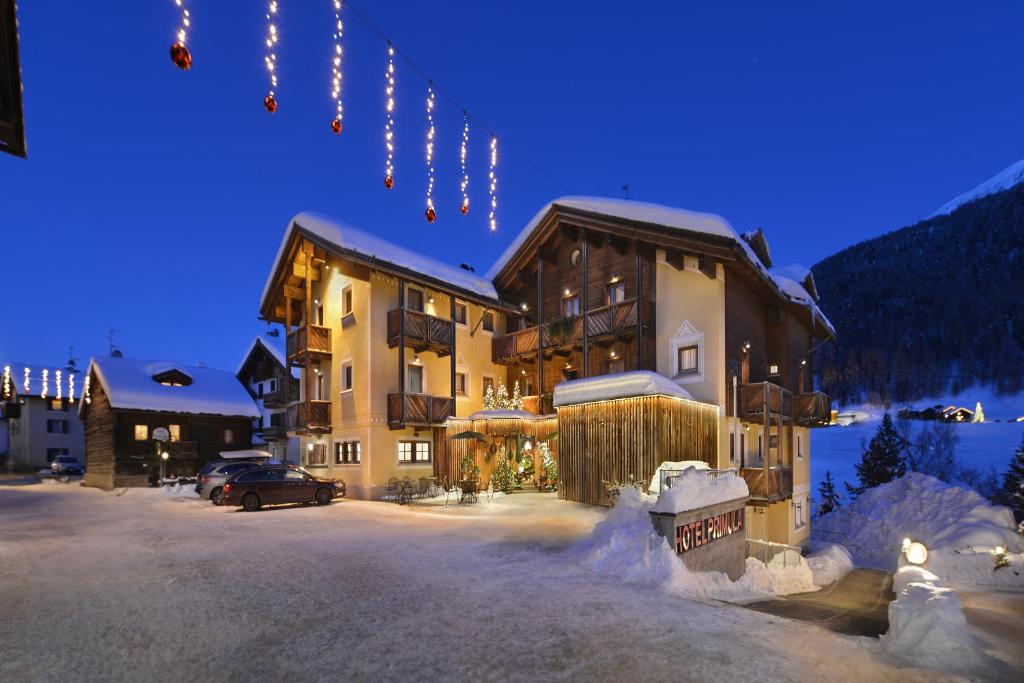 un gran edificio con nieve en el suelo y luces en Hotel Primula, en Livigno