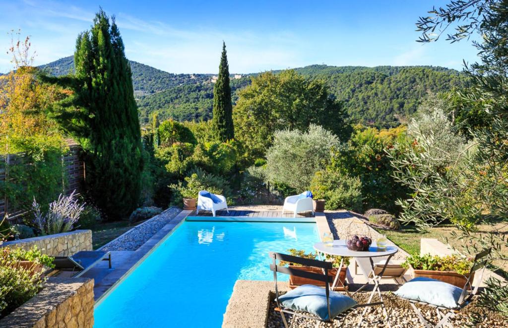 einen Pool in einem Garten mit einem Tisch und Stühlen in der Unterkunft Villa Marcelline in Saint-Marcellin-lès-Vaison