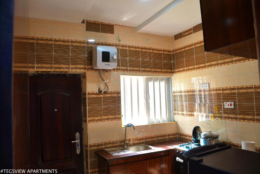 a small kitchen with a sink and a window at Tegsview Apartments, Ughelli in Ughelli