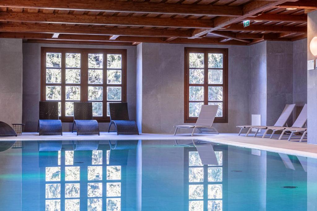 una piscina con sedie blu e finestre di Bergresort Gerlitzen by ALPS RESORTS a Treffen