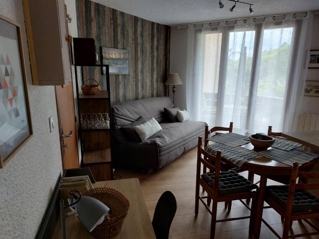 ein Wohnzimmer mit einem Sofa und einem Tisch in der Unterkunft Appartement en résidence proche du plan d'eau in Embrun