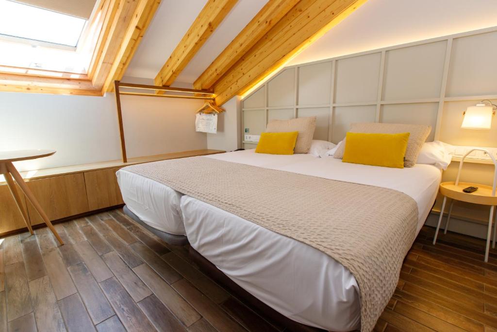 1 dormitorio con 1 cama blanca grande con almohadas amarillas en Hotel Pousada Real, en Caldas de Reis