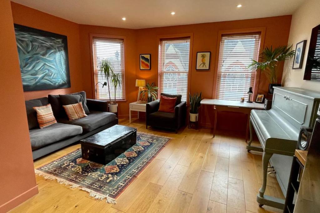 a living room with a couch and a piano at Charming and Spacious 2 Bed Near Kensal Green Tube in London