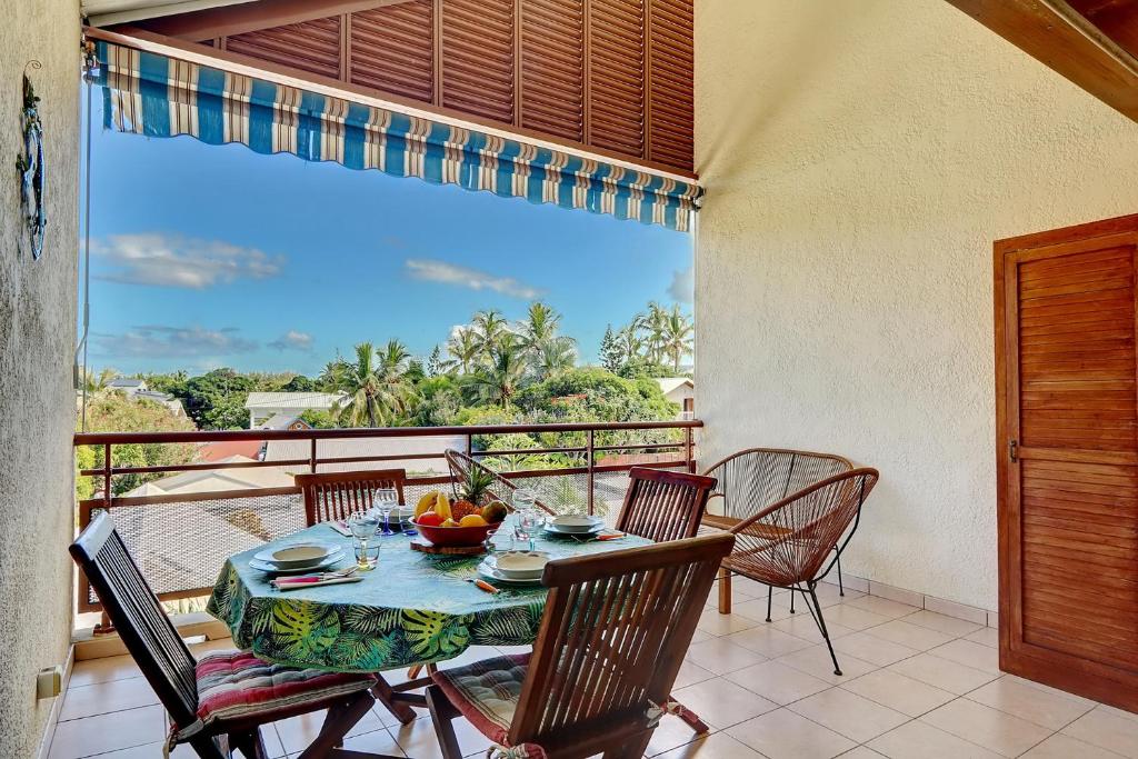 una sala da pranzo con tavolo e sedie sul balcone di Exceptionnel ! Le Kazuarina, Trés bel apt F3 à 50m de la plage de la Saline les Bains a La Saline Le Bains