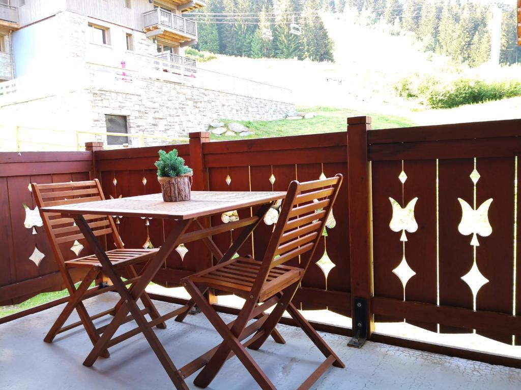 d'une table en bois et de deux chaises sur un balcon. dans l'établissement les 7 laux immobilier chalet D, à Prapoutel