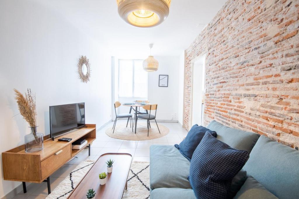 a living room with a blue couch and a brick wall at Parenthèse lumineuse au cœur d’Amboise in Amboise