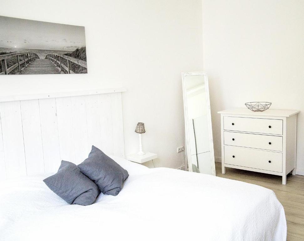 ein Schlafzimmer mit einem weißen Bett und einer weißen Kommode in der Unterkunft Ferienwohnung Charlotte in Glücksburg