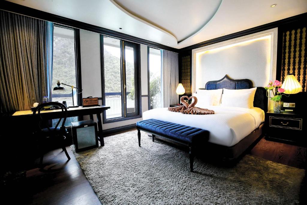 Lotus D'Orient Cruise في ها لونغ: غرفة نوم بسرير ومكتب ونوافذ