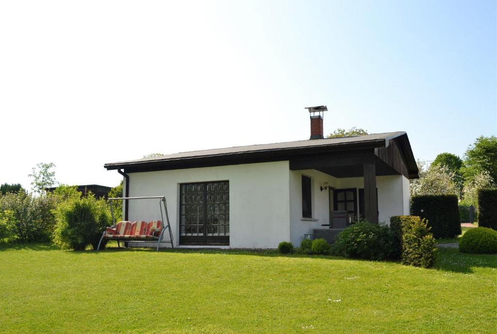 une petite maison blanche avec un banc dans une cour dans l'établissement Ferienhaus am See auf großem Grundstück, Kaminofen, à Krakow am See