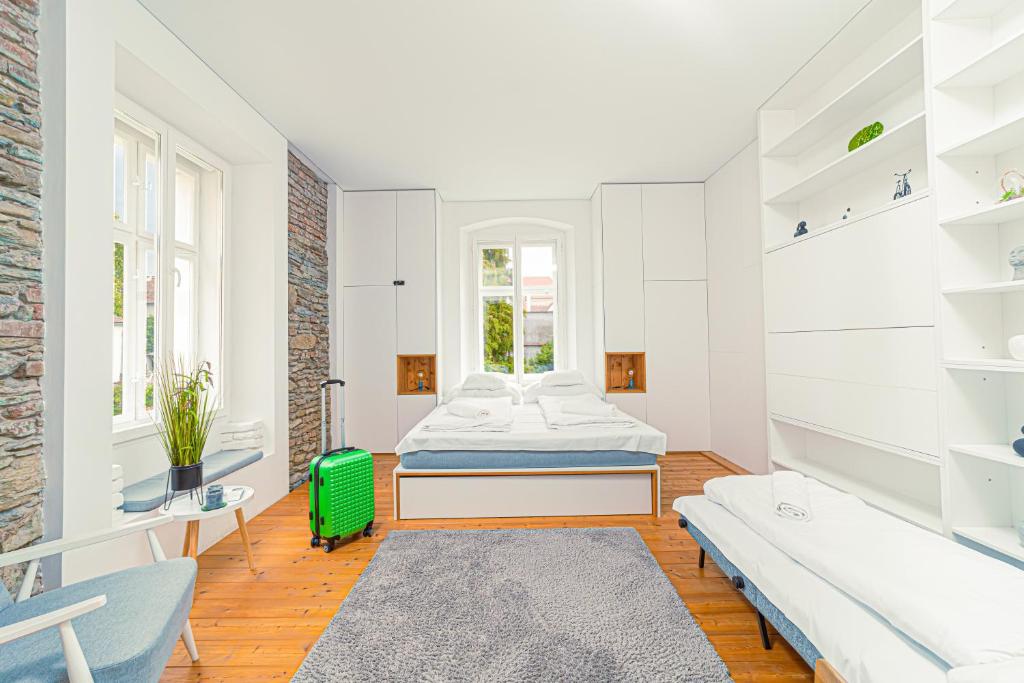 Habitación blanca con cama y maleta verde en Komló Apartman - Mátyás, en Kőszeg