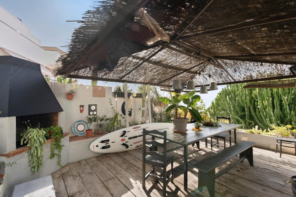 a patio with a table and a surfboard on a deck at Pardelo in Los Menores