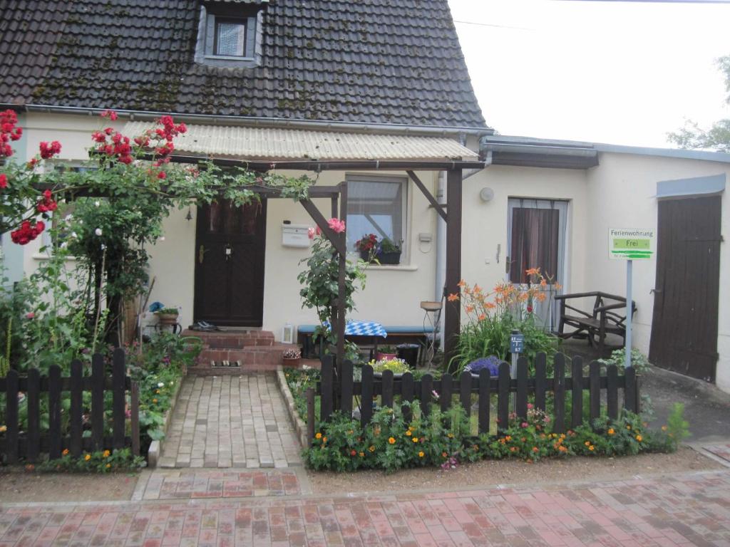 una pequeña casa blanca con una valla y flores en Gemütliche Ferienwohnung, separater Eingang, 