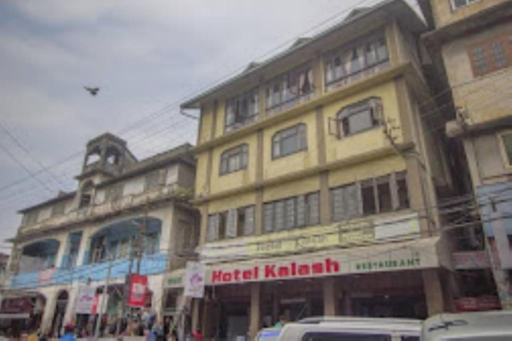 ein großes gelbes Gebäude in einer Stadtstraße in der Unterkunft Hotel Kalash , Kalimpong in Kalimpong