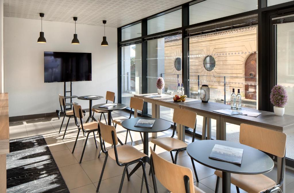 a restaurant with tables and chairs and a bar at Ténéo Apparthôtel Bordeaux Maritime - Cité du vin in Bordeaux